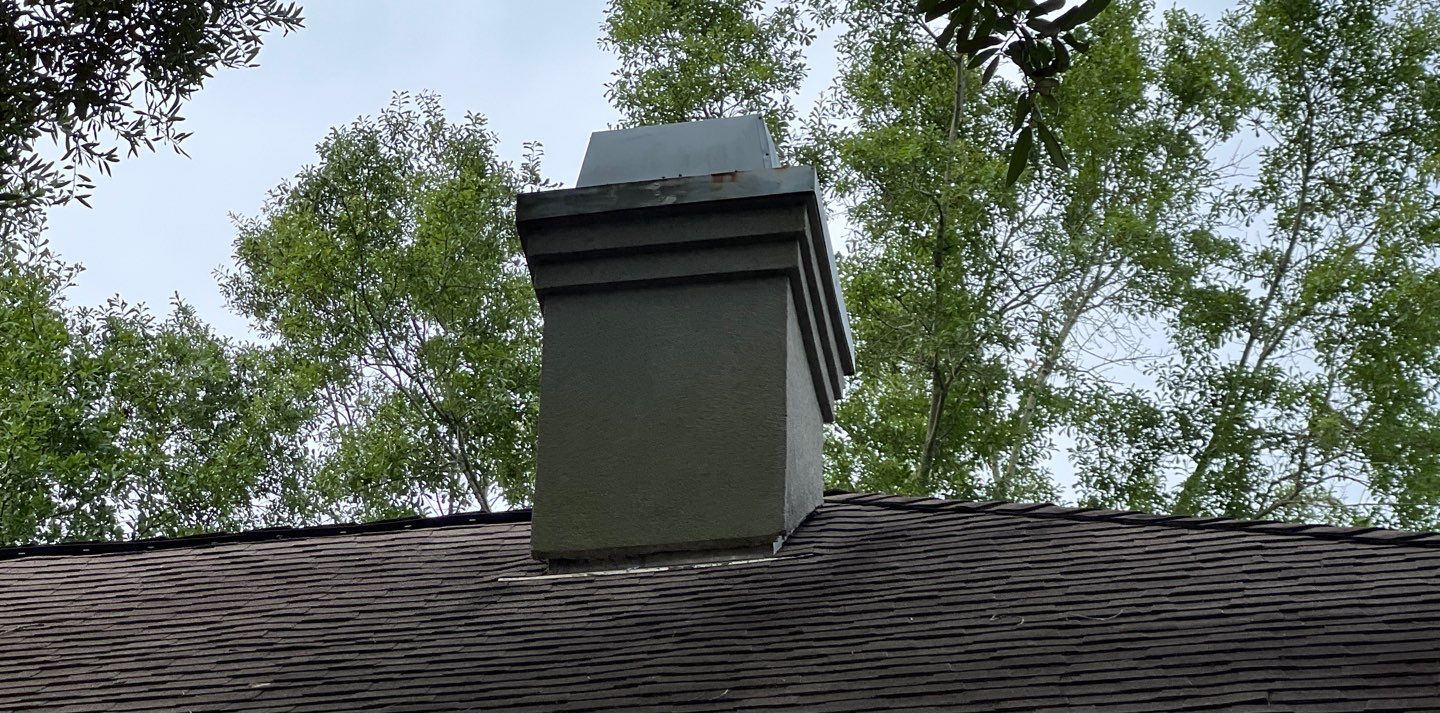 The chimney of the Biloxi home on the old worn shingle roof, its flashing installed but not installed right