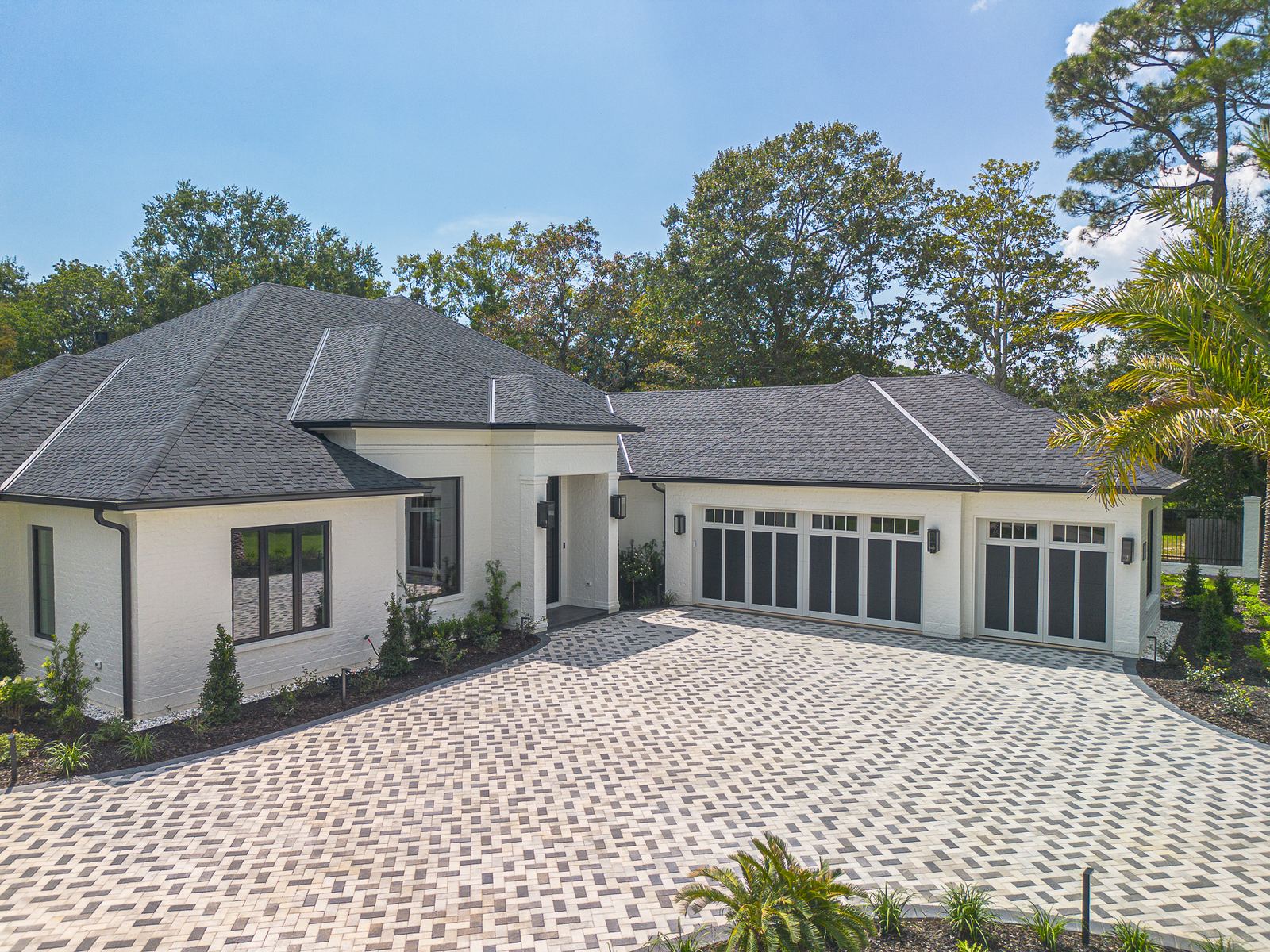 The new home and its paver driveway under the completed charcoal designer shingle roof