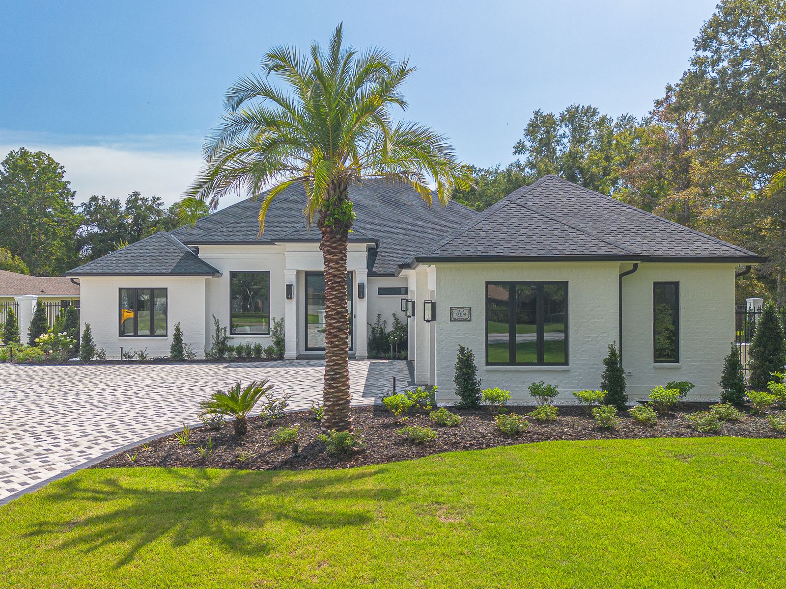 Front elevation of the new Ocean Springs home with palms and the charcoal shake roof