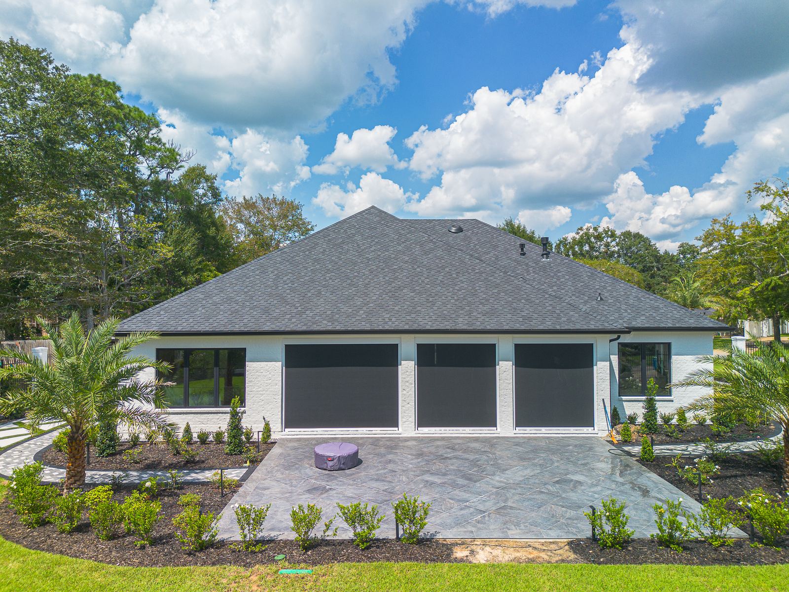 Front elevation of the white home with the charcoal designer shingle roof over the three-car garage