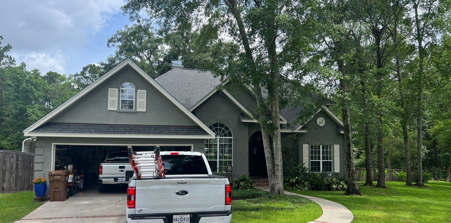 The stucco and brick Woolmarket home in Biloxi from the drive under its completed FORTIFIED Georgetown Gray shingle roof