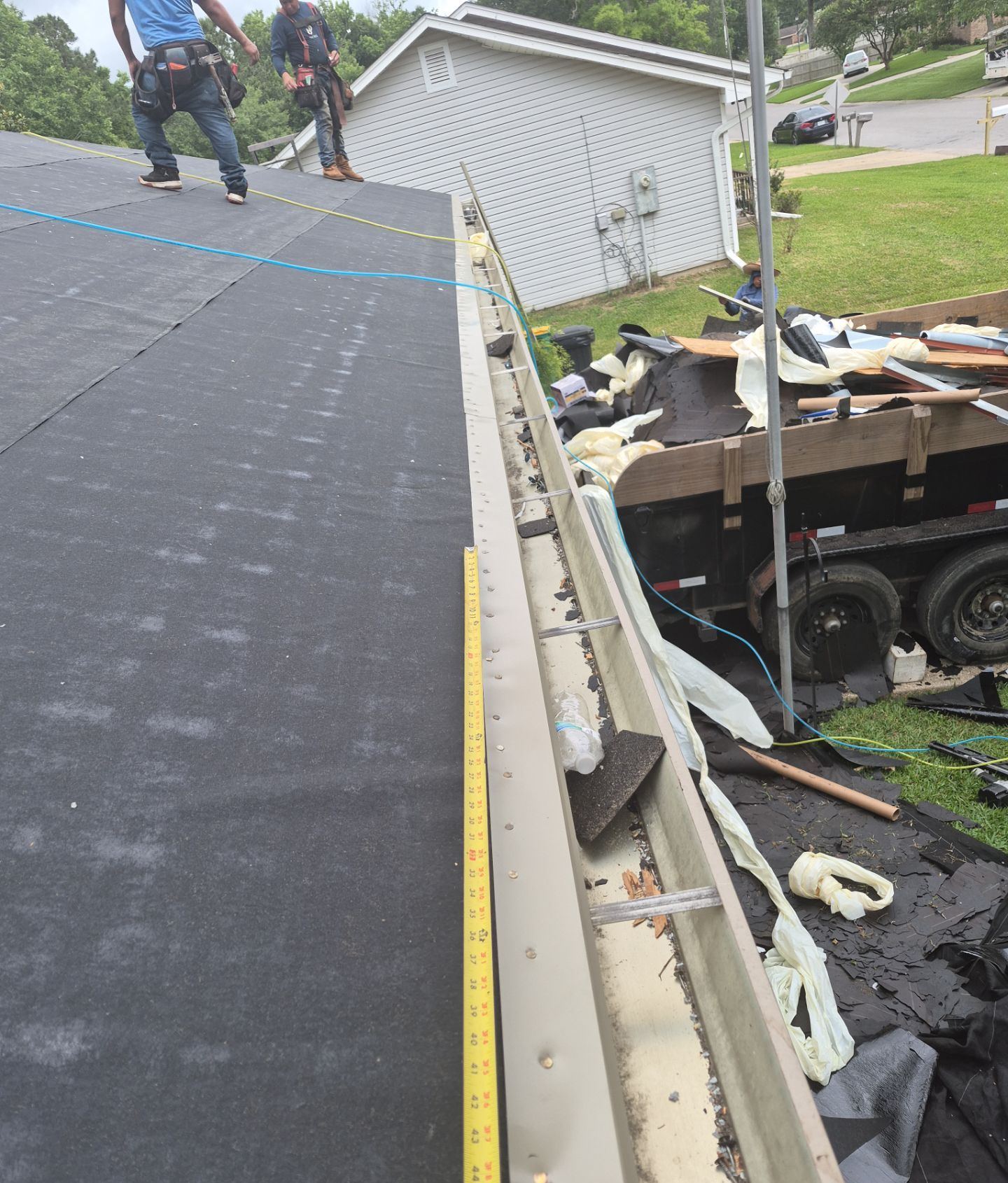 The sealed roof deck and new tan drip edge along the eave of the Long Beach home, a tape measure at the fasteners