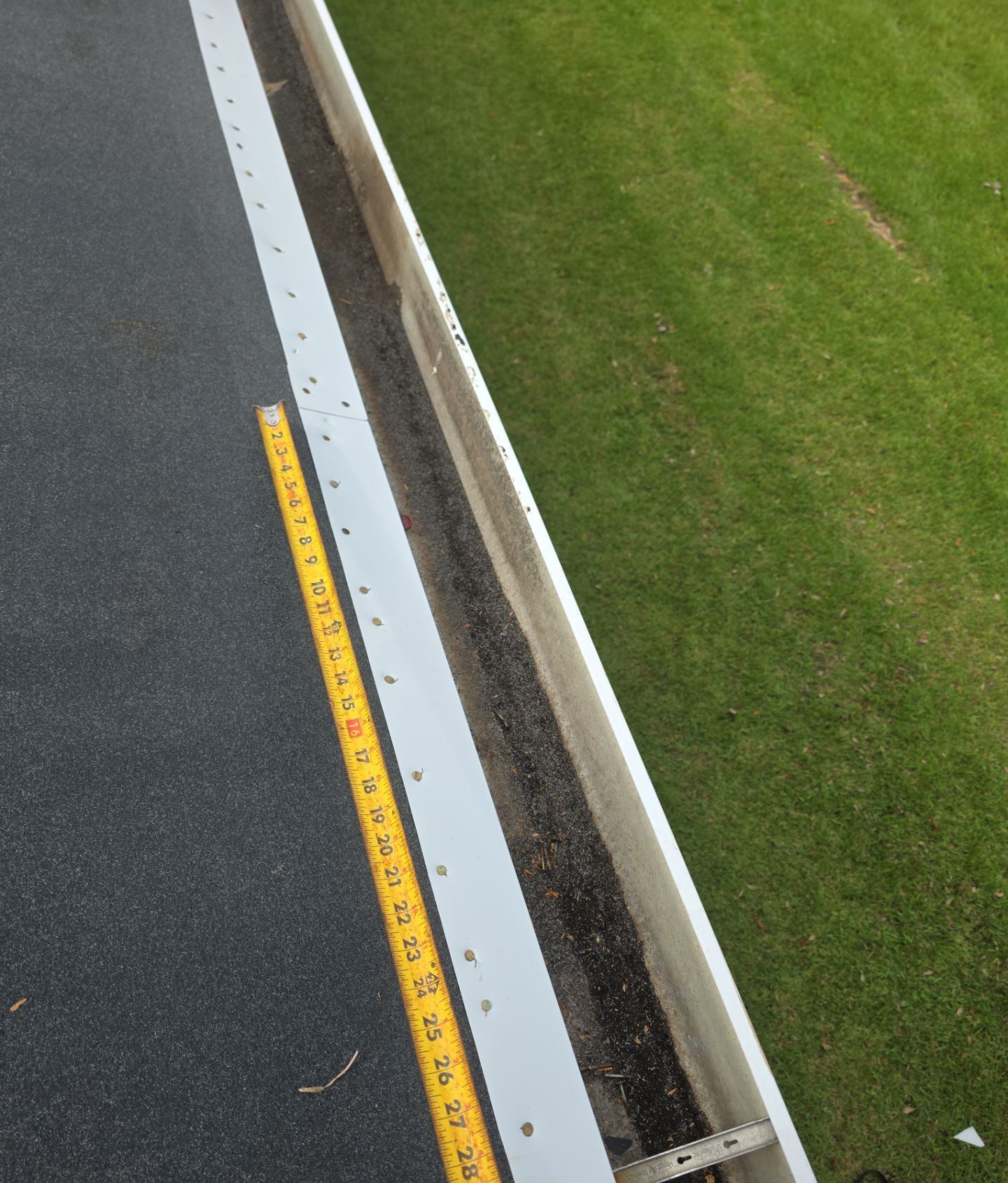 A tape measure along the new drip edge on the Pascagoula roof documenting the four-inch fastener spacing