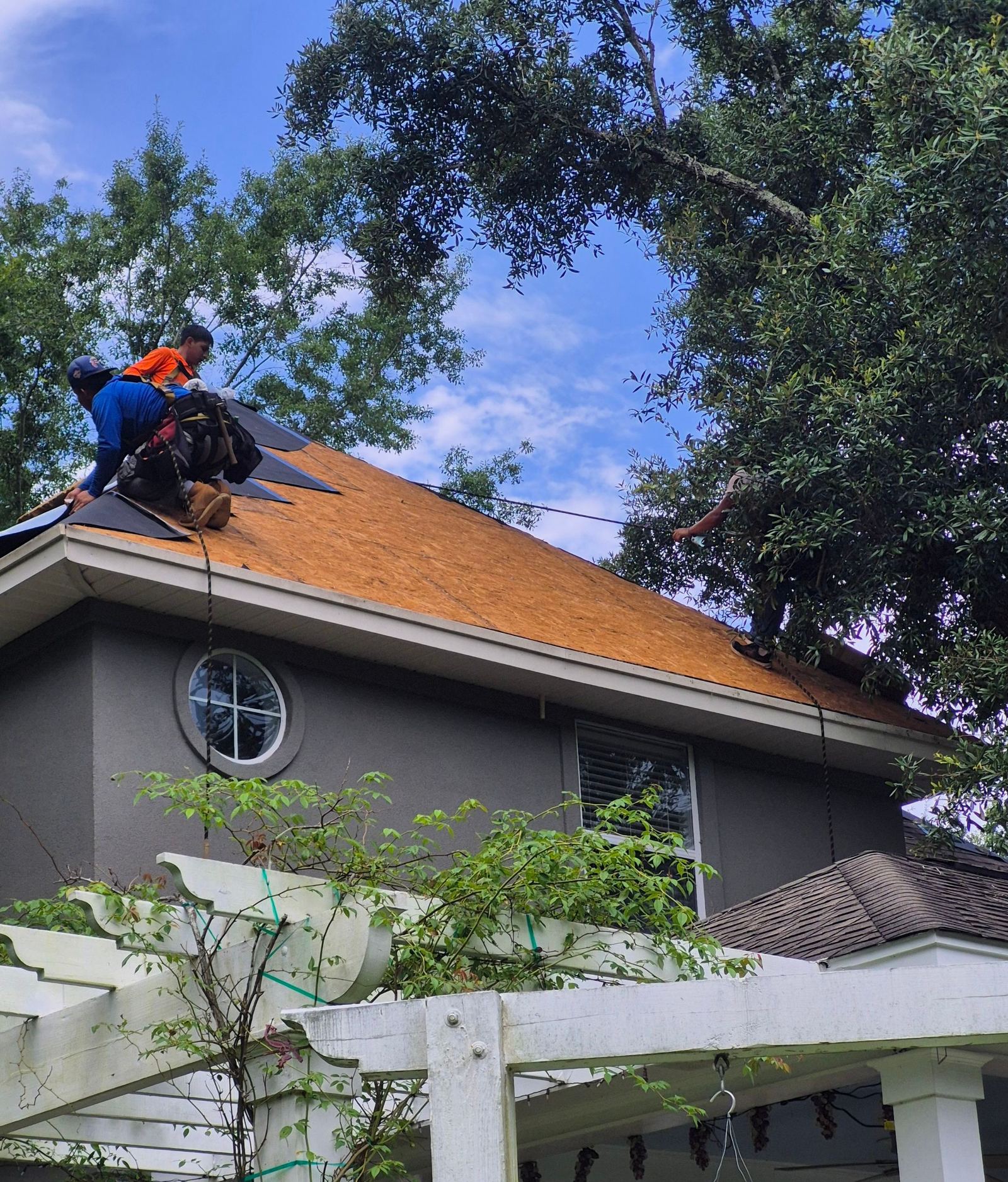 The crew tearing off the old roof above the pergola of the Biloxi home, deck exposed