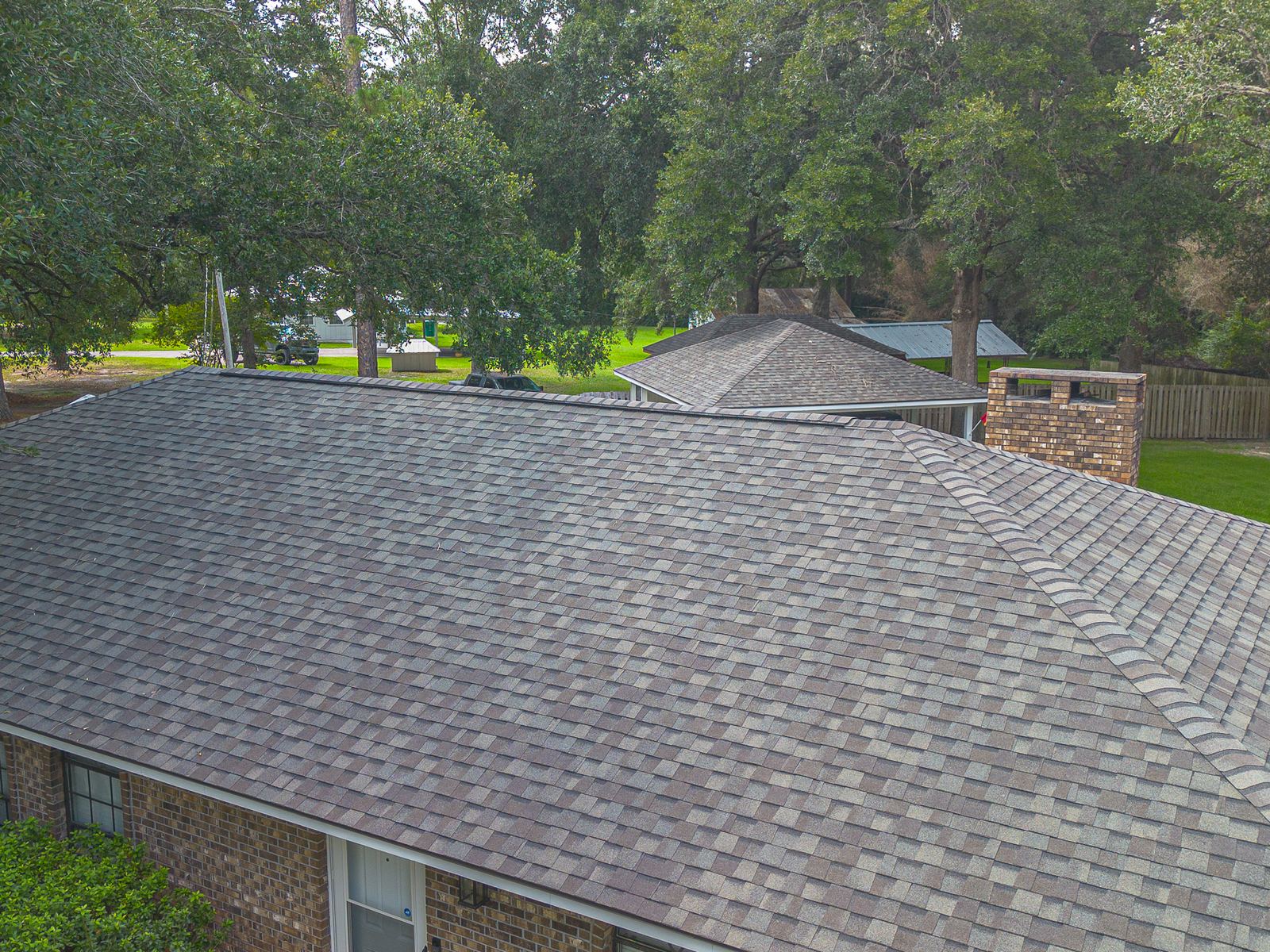 Aerial of a brick Ocean Springs home after a FORTIFIED shingle replacement, new CertainTeed Landmark Weatherwood shingles and chimney flashing