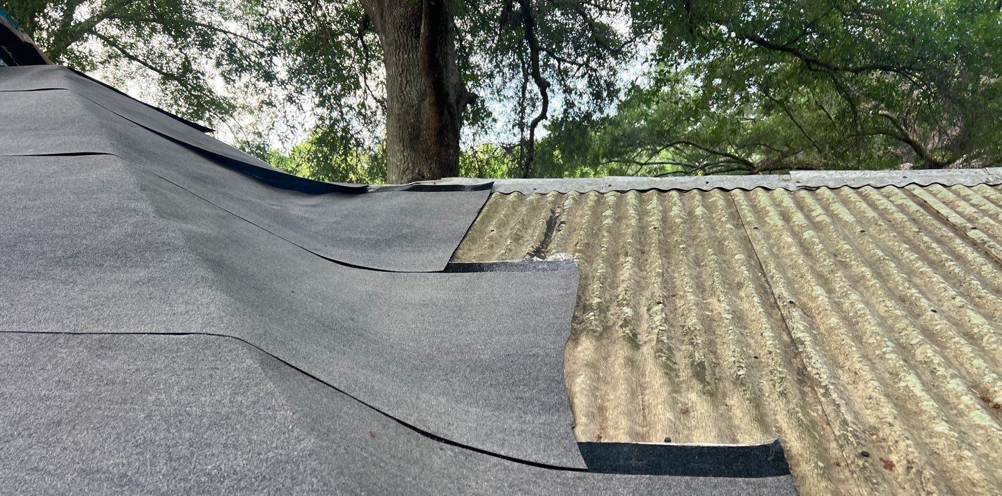 Old three-tab shingles peeled back during tear-off, exposing the original plank roof deck of the Ocean Springs home