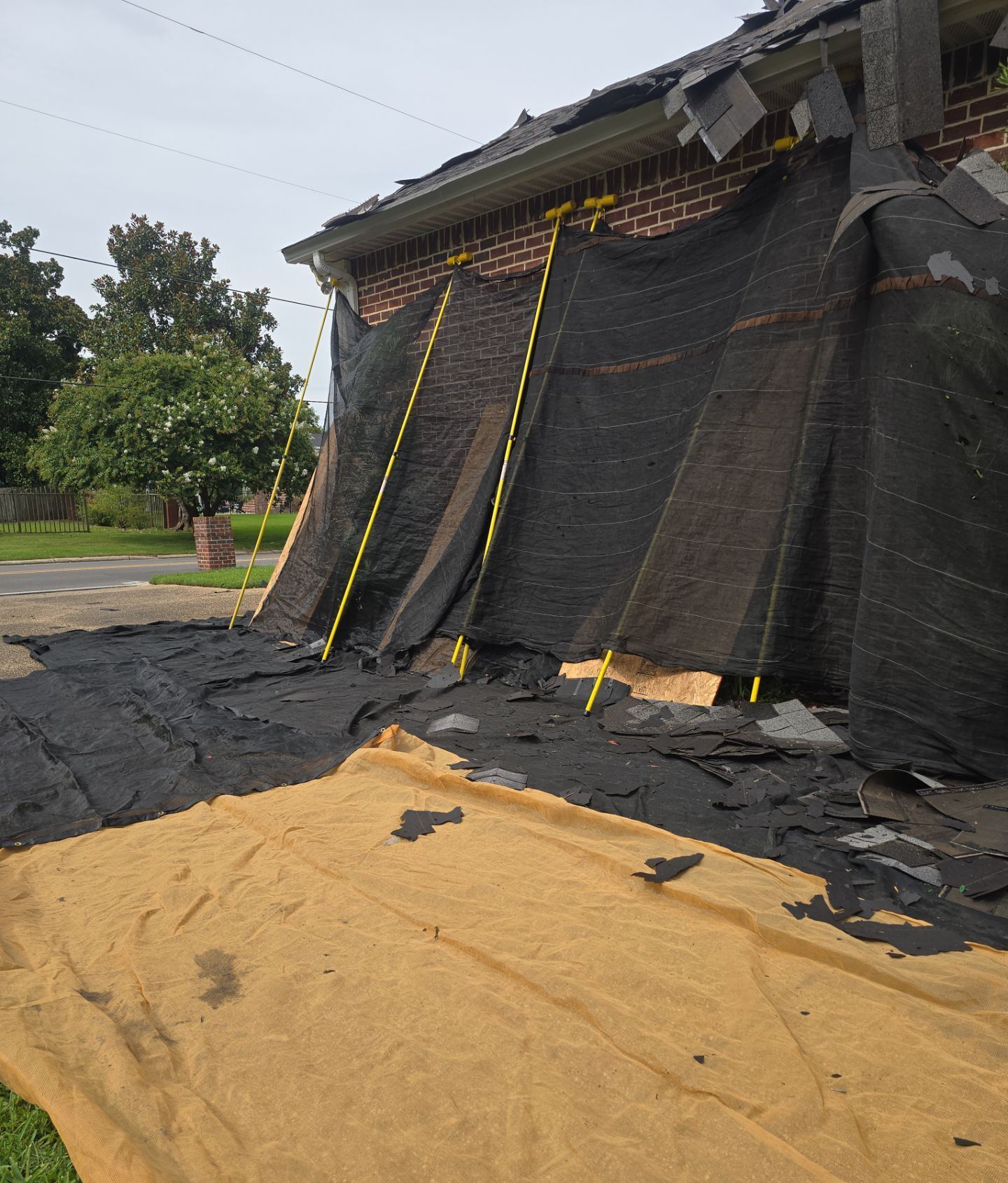 Tarps draped over the front of the Pascagoula home catching old shingles during the tear-off