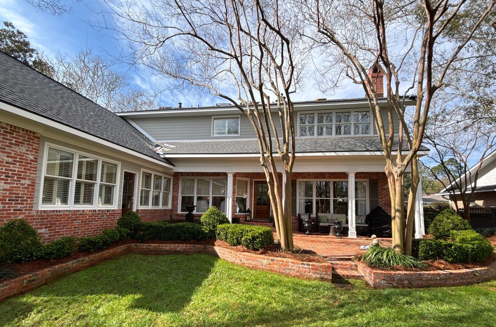 Rear of the Gulfport home under the new Pewter Gray shingle roof, brick chimney and crape myrtles in the sun