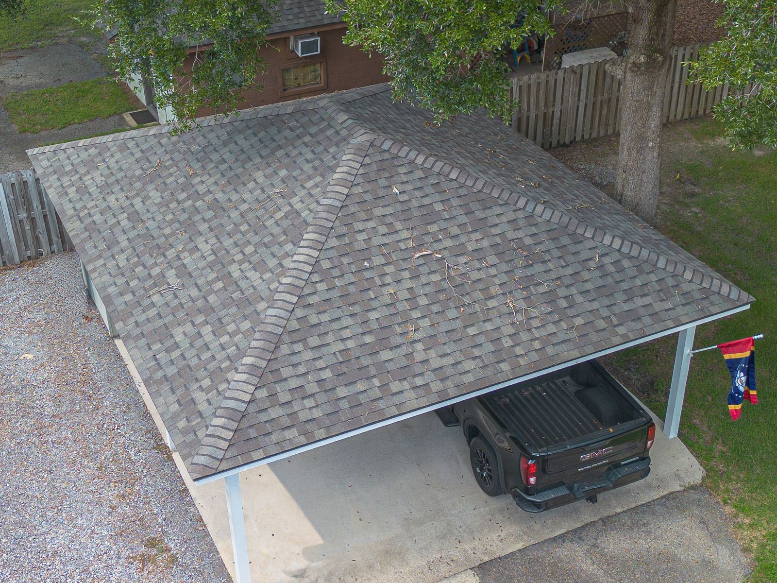 The detached carport with its new hip roof in matching Weatherwood shingles, truck parked beneath