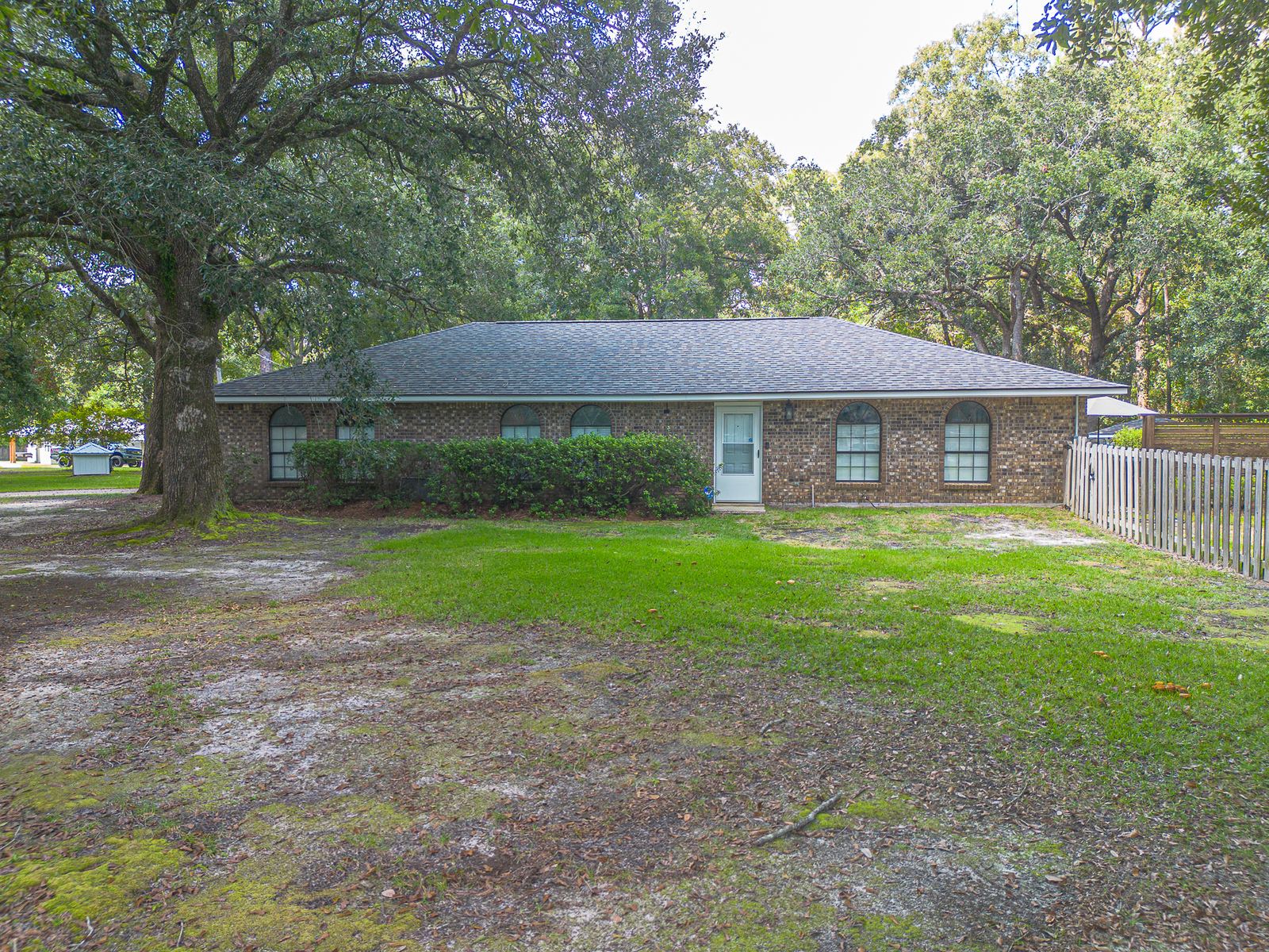Rear elevation of the brick home under live oaks after the FORTIFIED shingle replacement