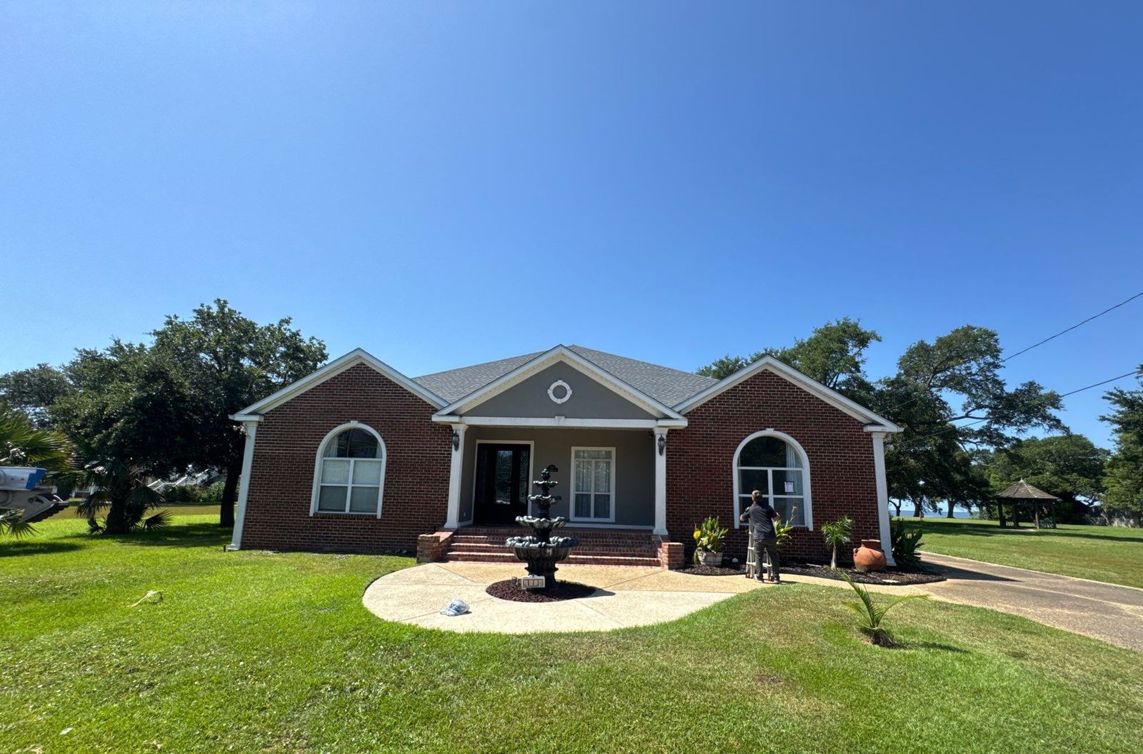 Front elevation of the brick Pascagoula home and its fountain under the completed FORTIFIED Pewter Gray shingle roof