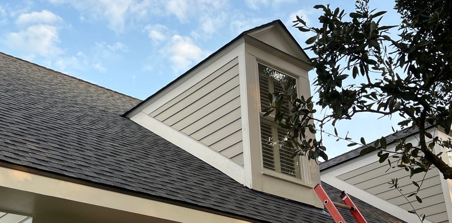 One of the two dormers on the Gulfport home before replacement, the old charcoal shingle roof meeting the dormer wall