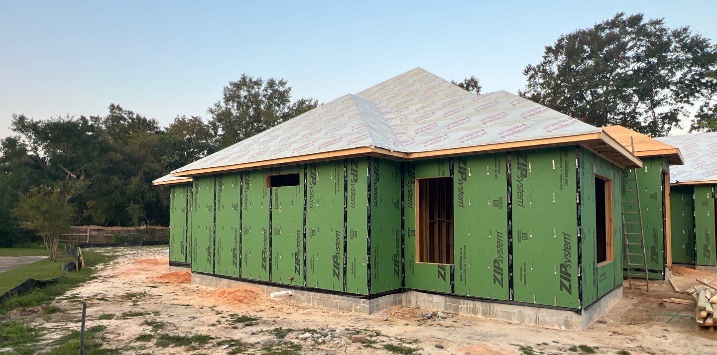 The Ocean Springs new build at framing stage with a bare roof deck and sheathed walls before the roof went on