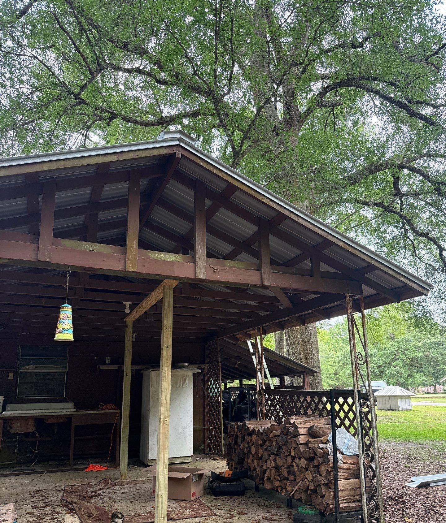 The low patio lean-to behind the detached office before replacement, its old roof sagging over the wood frame