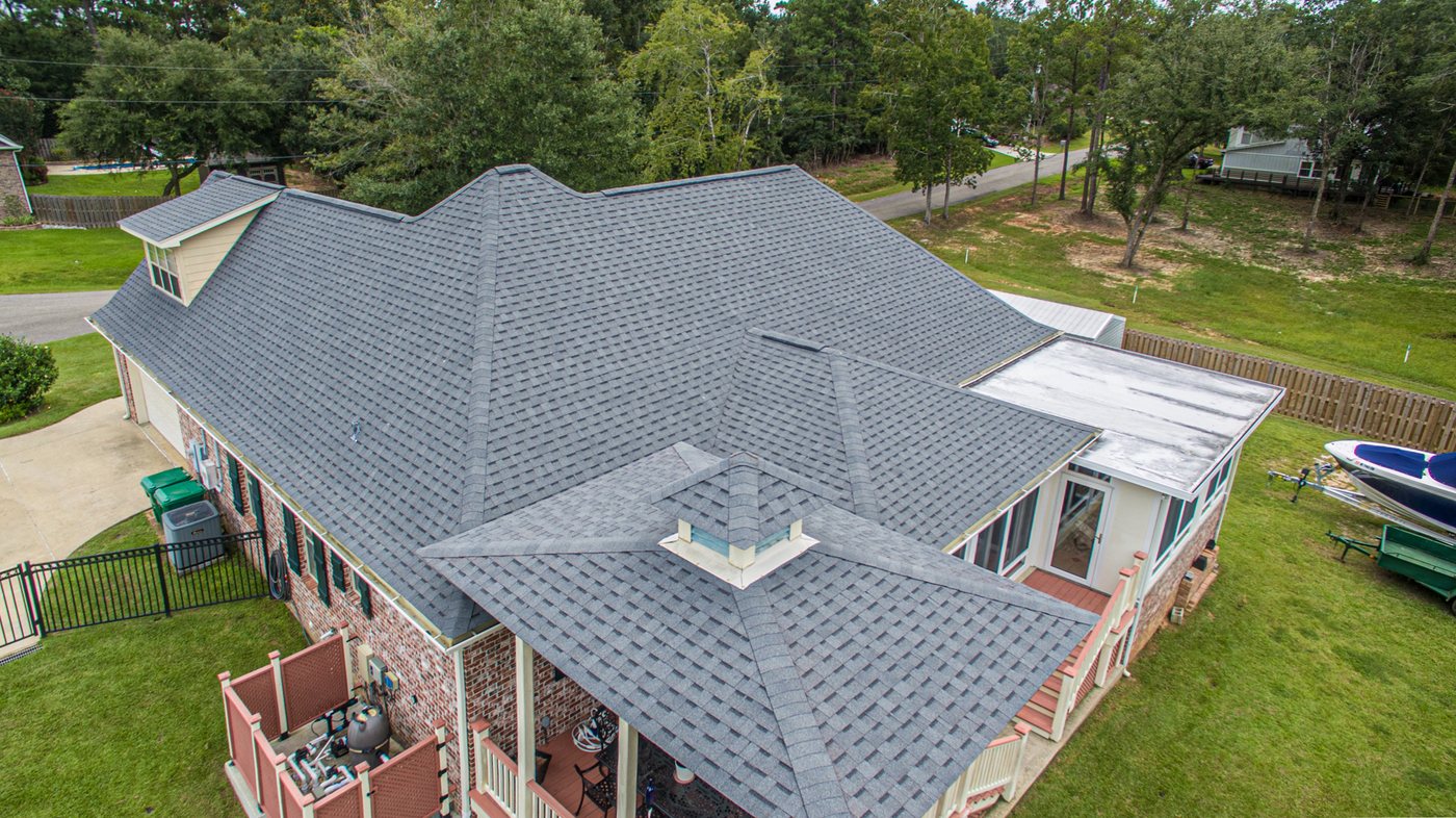 Angled drone view of a completed architectural shingle roof replacement on a Diamondhead Mississippi home, showing the hip and ridge lines across the full roof