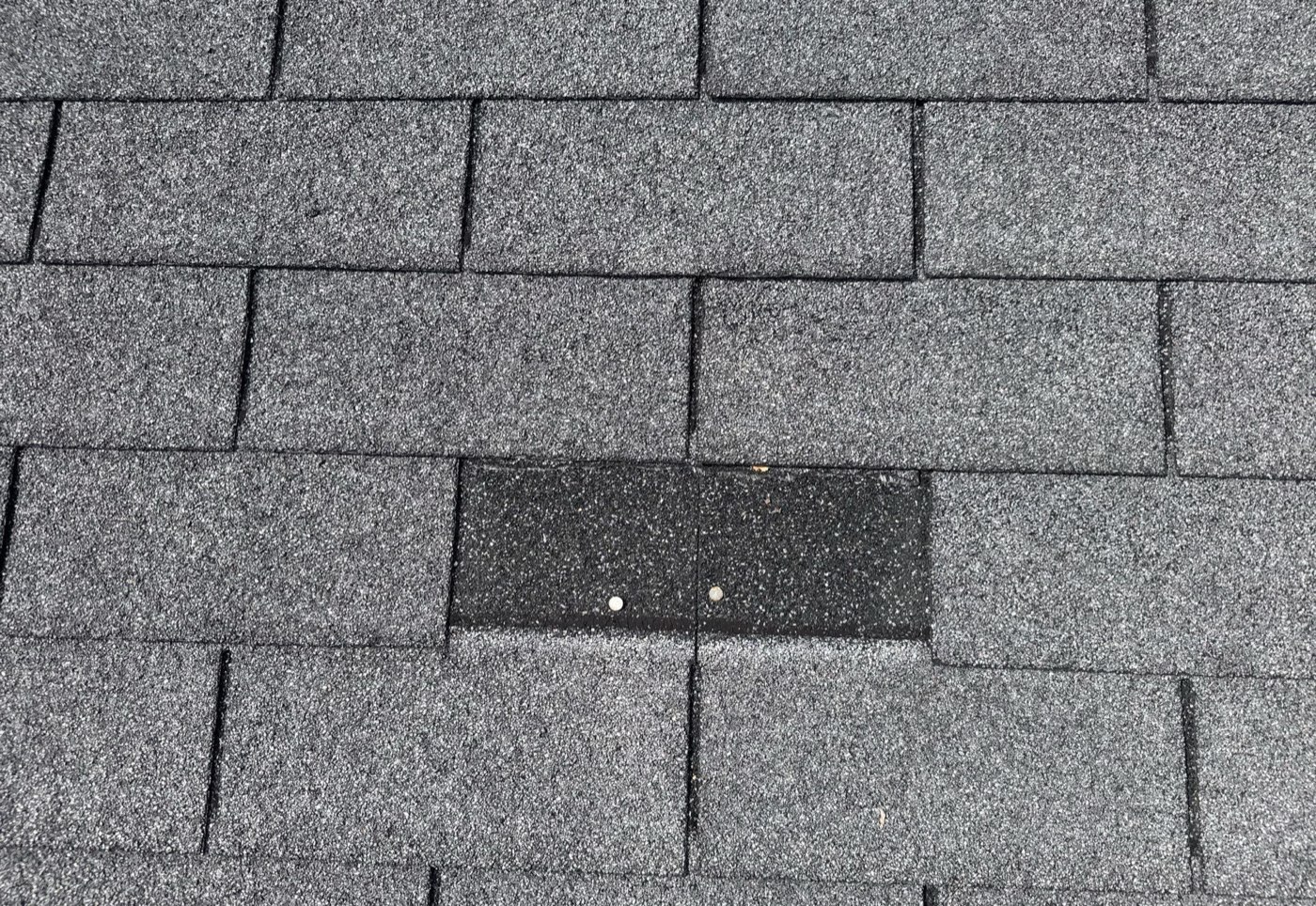 Missing architectural shingle tab exposing the underlayment on a Gulf Coast Mississippi roof before repair