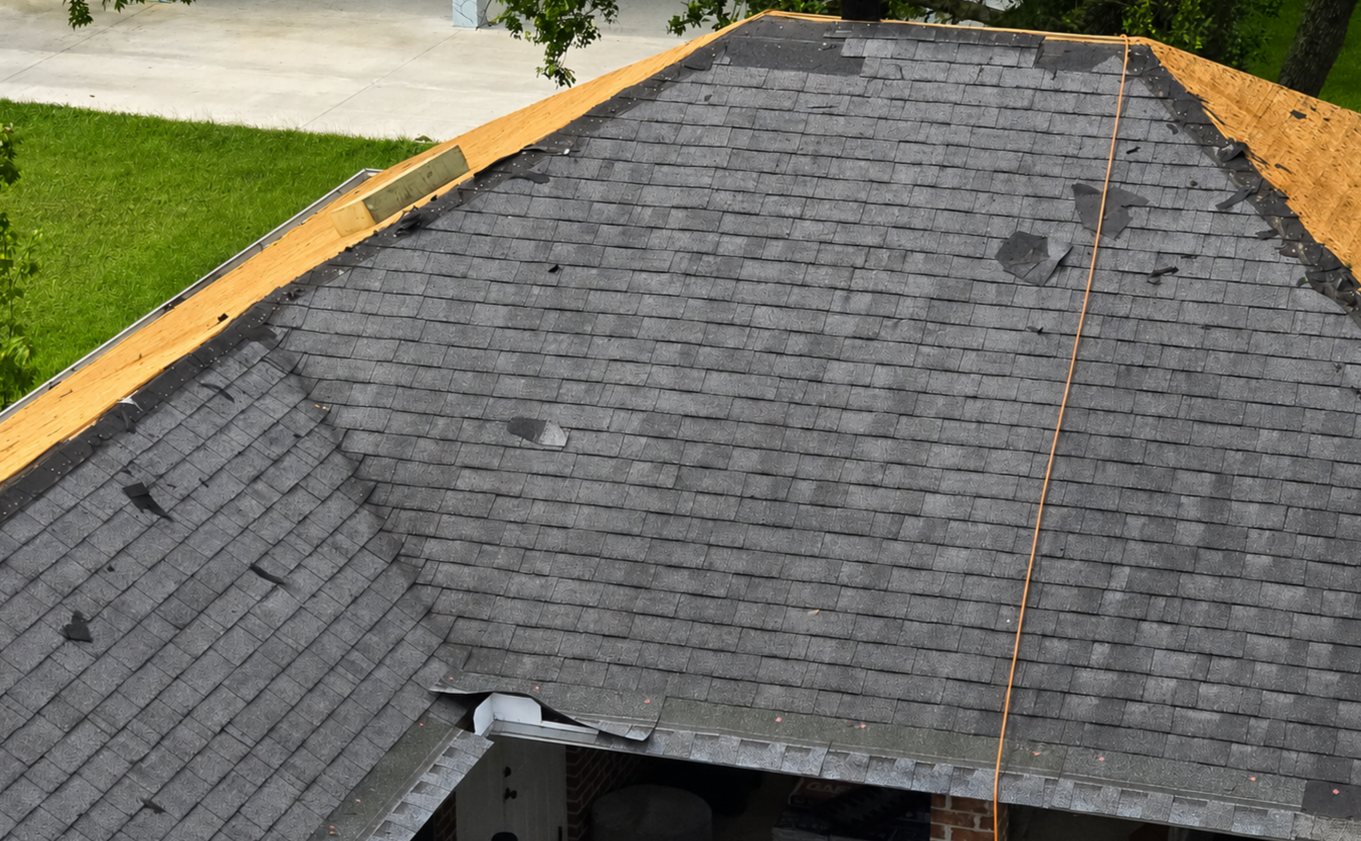 Old three-tab shingles coming off down to the bare deck during a Gulf South Roofing tear-off on the Mississippi Gulf Coast