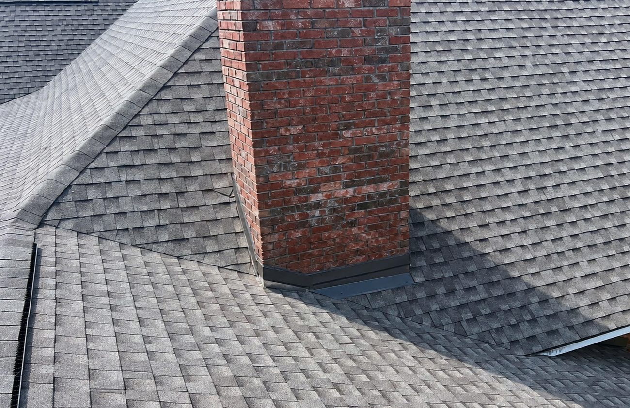 New step and counter flashing fitted around a brick chimney on an architectural shingle roof, Mississippi Gulf Coast
