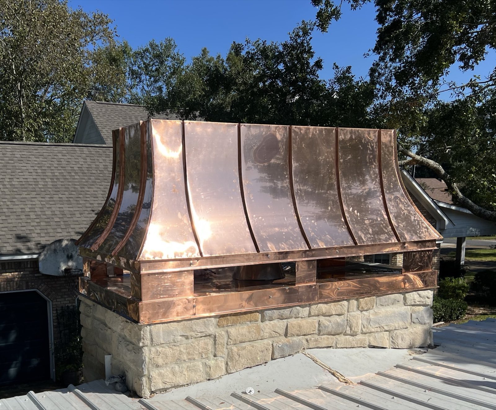 Custom copper chimney hood fabricated and installed by Gulf South Roofing on a stone chimney on the Mississippi Gulf Coast