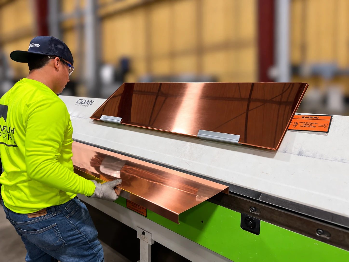 A Gulf South Roofing fabricator bending copper flashing on the brake in the company's Gulfport sheet metal shop