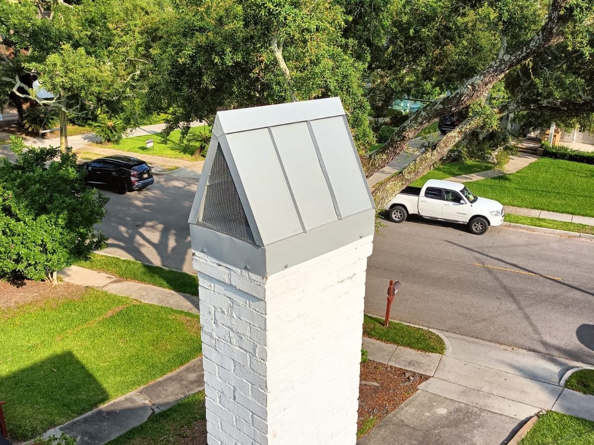 Custom sheet metal chimney cap and hood with a screened vent on a white brick chimney, Mississippi Gulf Coast
