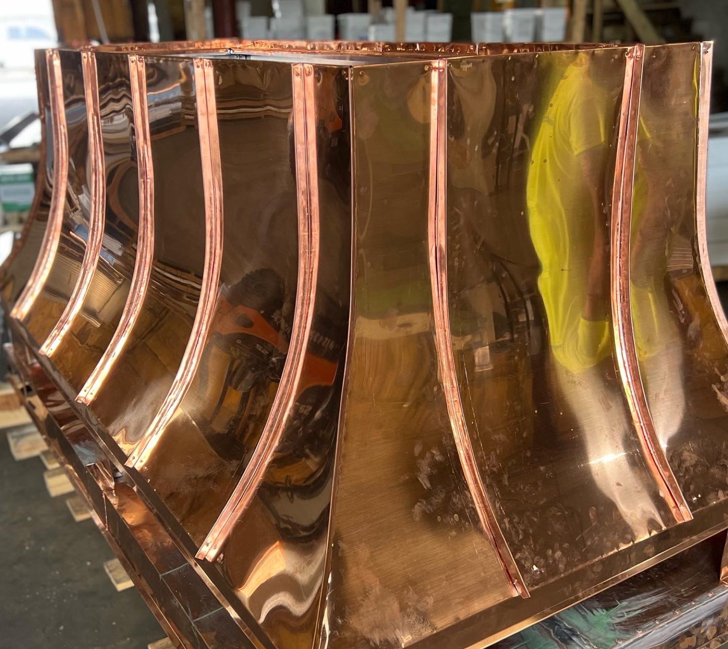 Fabricator soldering seams on a custom copper chimney hood