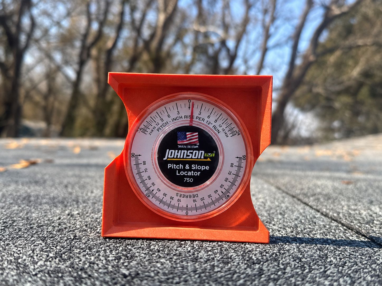 A pitch and slope gauge set on a low-slope shingle roof section, reading the actual pitch against the shingle minimum