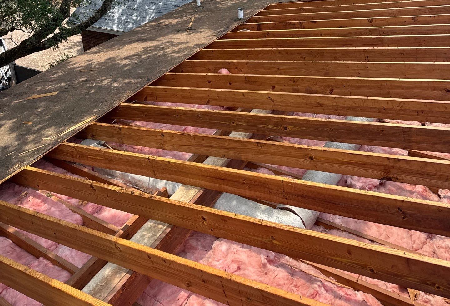 Exposed rafters and new sheathing on a low-slope section of a Gulf Coast home, the old deck stripped back before the membrane goes down