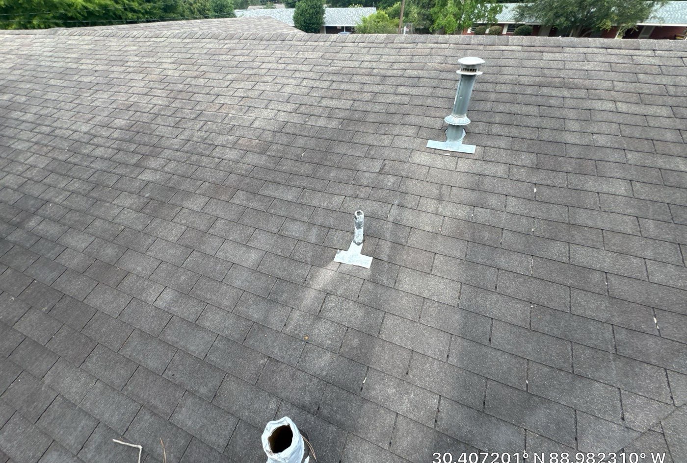 Weathered low-slope roof field with aging pipe boots on the Mississippi Gulf Coast