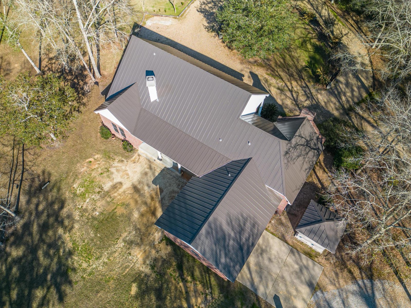 Top-down aerial of a completed residential standing seam metal roof by Gulf South Roofing showing the full hip-and-valley roof plan
